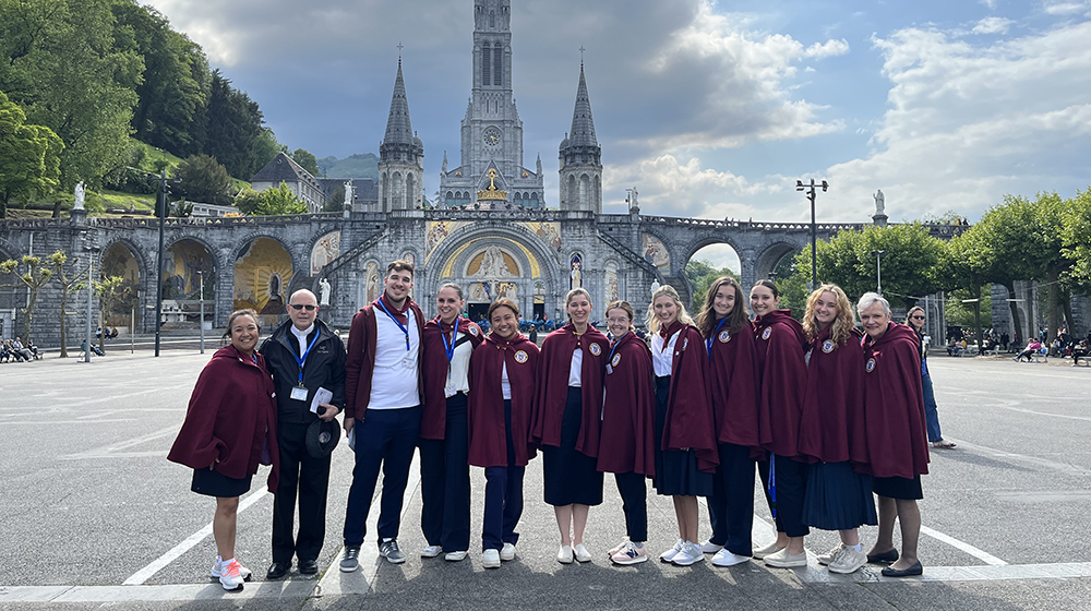 Students pose in front of a cathedral in Lourdes